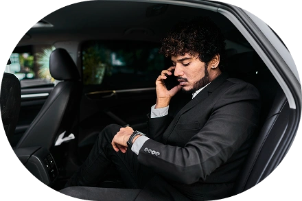 Biznes səfəri zamanı avtomobilin arxa oturacağında oturan və telefonda danışan bir iş adamı