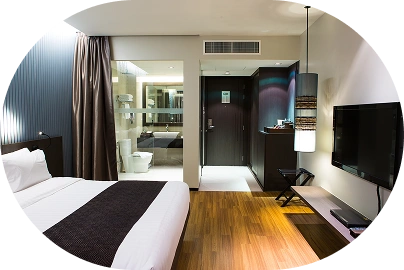 Taxta döşəməli və inteqrasiya olunmuş hamam sahəsi olan müasir otel üslubunda yataq otağı interyeri.